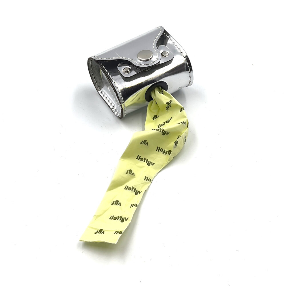 Hundeposeholder i sølv set nedefra med plads til to ruller poser og med en illustration af en mynde, der skider på siden.